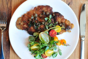 Pork chop Milanese with tomato, capers and arugula salad