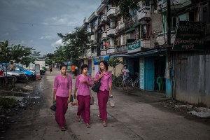 Garment factory workers walk to work from their dormitories on October 13, 2015. On August 29 2015, the government of Myanmar announced a minimum wage of 3,600 kyats (about 3 US$). This slight pay raise was met with hostilities by factory owners in the Garment Industries who either refused to increase pay at all, made layoffs to keep expenses the same or cut overtime pay and benefits. Even those garment factory workers who have seen a increase in their daily wages have seen very little change in their salaries overall.