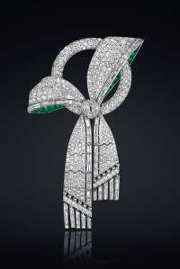 An art deco diamond and emerald bow brooch.