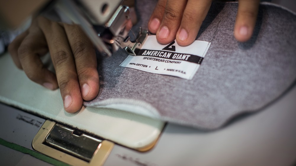 Sewing on the American Giant label.