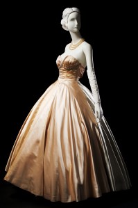 Women's strapless, floor-length evening ball gown designed by Mainbocher in 1951. Dress of pale pink, blue, and gray silk satin with high-waisted, fitted bodice trimmed with pearl and rhinestone band.
