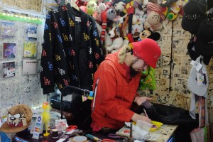 Hayatochiri owner Gotō Yoshimitsu studs clothing behind the store's cash wrap.