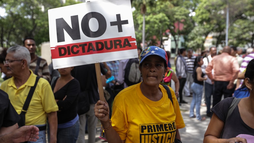 A woman carries a sign that reads ?No Dictatorship? during a protest in Caracas, Venezuela, 31 March 2017. Several protests broke out after a Supreme Court ruling took power from congress raising fear of a dictatorship. The ruling is being condemned by opponents of President Nicolas Maduro and foreign governments.Demonstrations erupt in Venezuela after the Supreme Court's rulings, Caracas - 31 Mar 2017