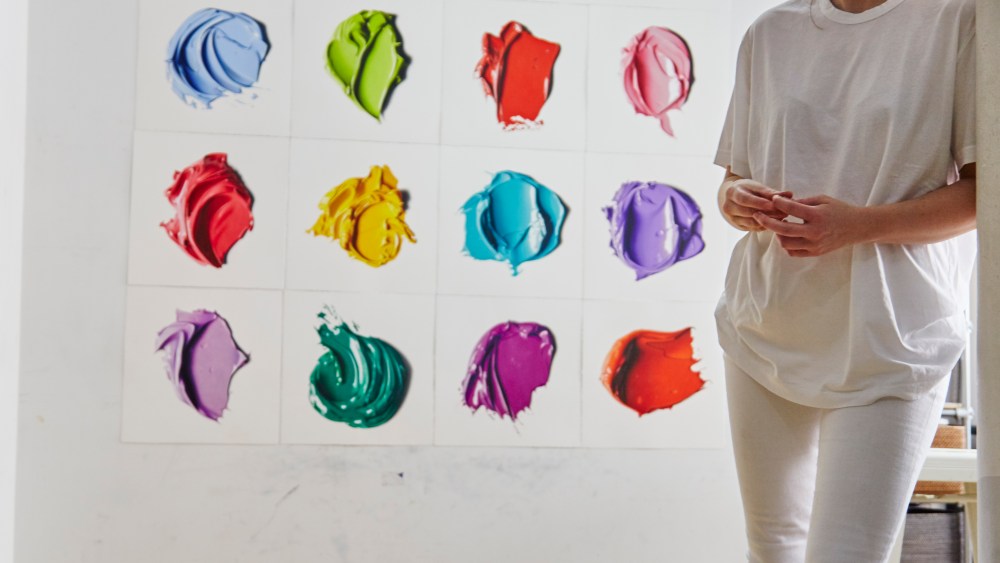 The artist CJ Hendry standing in front of her hyperrealistic drawings.