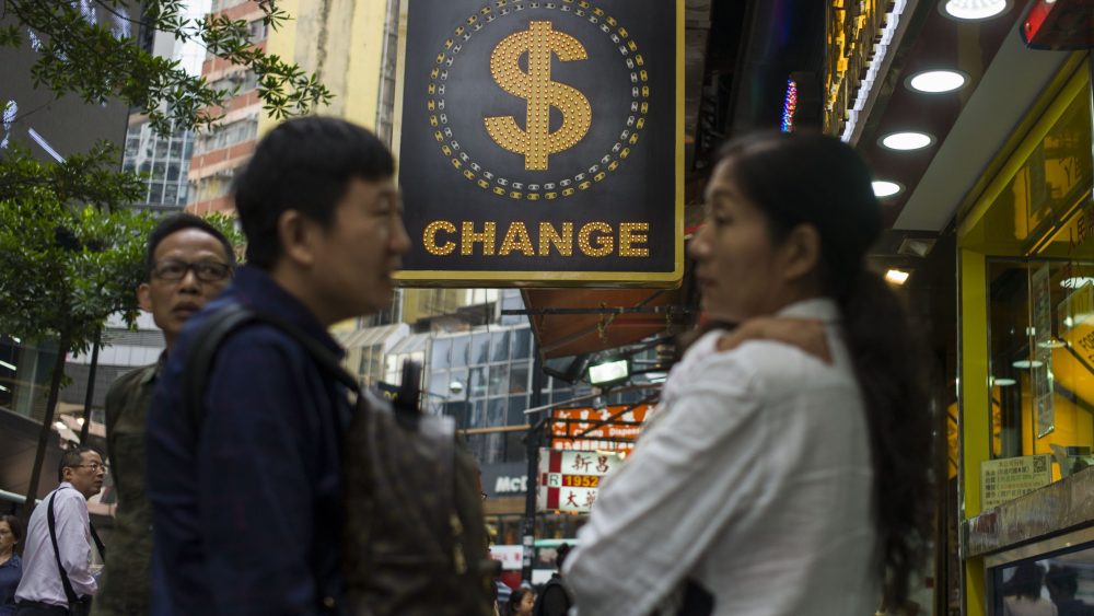 People chat next to a currency exchange shop in Causeway Bay, Hong Kong.