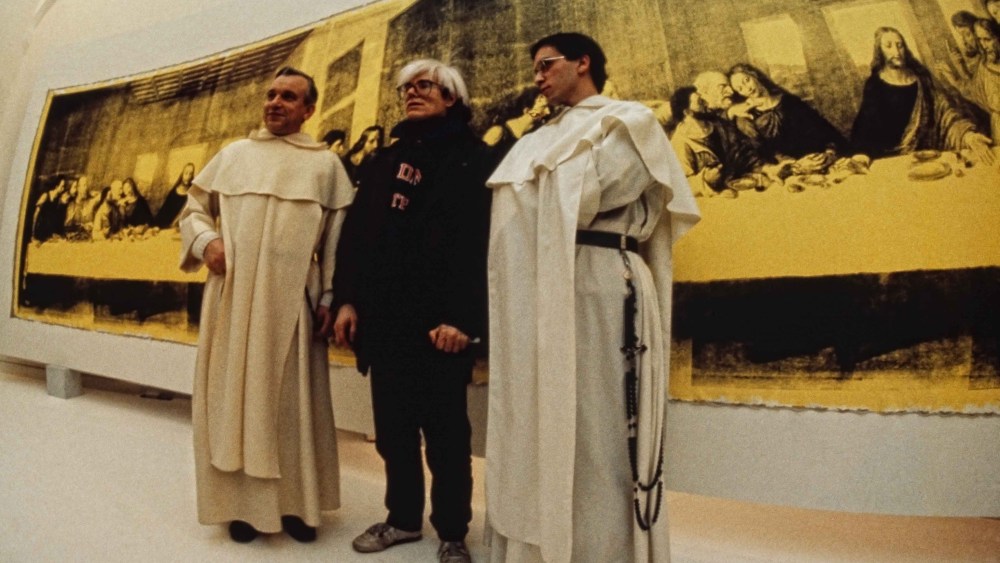 Andy Warhol in front of The Last Supper (Yellow) (1986) at the opening of Andy Warhol – Il Cenacolo at Palazzo delle Stelline, Milan, January 22, 1987.