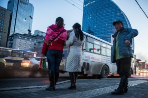 Mongolian men and women wait to cross a street in Ulaanbaatar, Mongolia on March 19, 2017. Photographer: Taylor Weidman