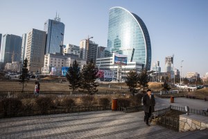 A commuter walks through a park near Blue Sky Tower in Ulaanbaatar, Mongolia on March 20, 2017. Photographer: Taylor Weidman