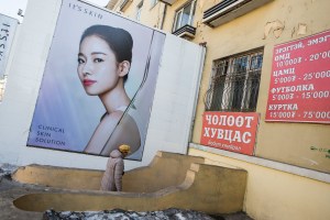 A woman walks past a billboard near the State Department Store in Ulaanbaatar, Mongolia on March 19, 2017. Photographer: Taylor Weidman