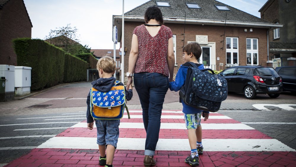 Model Released - Young woman accompanying her kids as they cross the road on their way to schoolSeptember and back to school