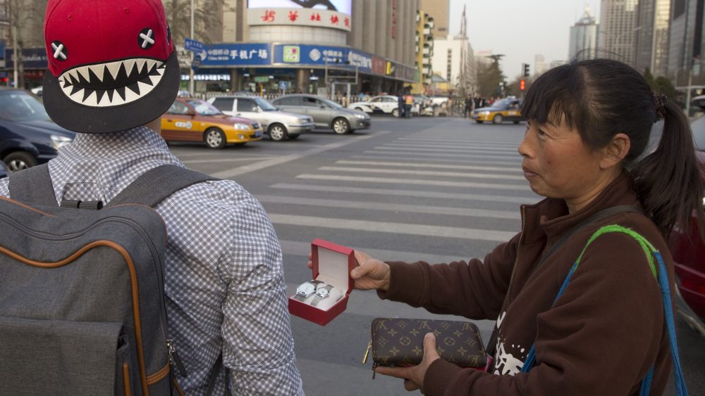 A street vendor hawks counterfeit branded items to tourists on the streets of Beijing.
