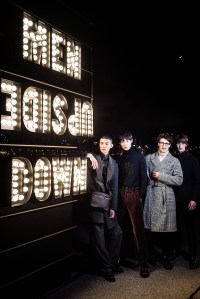 Models pose beside a sign that reads "Men Upside Down".