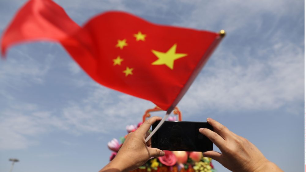 A Chinese tourist holds a Chinese national flag and uses their mobile phone to take a photograph in Tiananmen Square during National Day celebrations in Beijing, China, 01 October 2017. China celebrates its National Day on 01 October, marking its 68th founding anniversary.National Day celebrations in Beijing, China - 01 Oct 2017