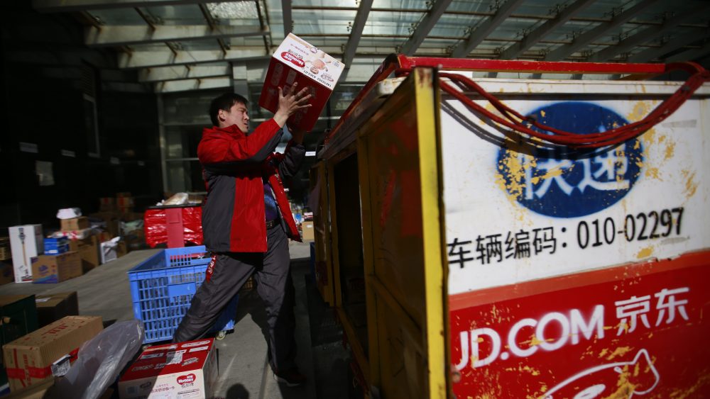 A Chinese messenger transfer packages into his three-wheel delivery cart at a distribution centre for JD.com on Singles' Day.