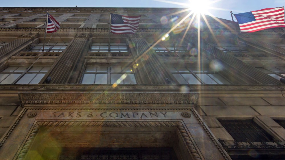 The sun shines through flags on the facade of Saks flagship store on New York's Fifth Avenue, . Saks Inc. agreed to sell itself to Hudson's Bay Co., the Canadian parent of upscale retailer Lord & Taylor, for about $2.4 billion in a deal that will bring luxury to more North American localesSaks Acquisition, New York, USA