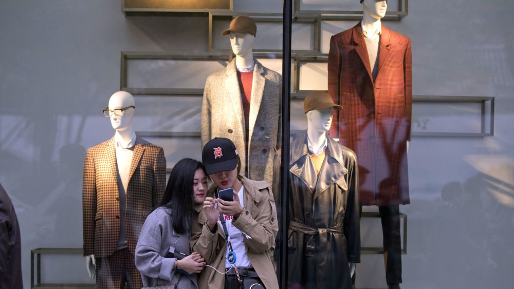 Women look at their mobile phones near mannequins showing the latest fashion in a retail street of the Chinese capital where the 19th Party Congress is held in Beijing, China, . China has succeeded in leveraging its booming economy and mountain of foreign currency holdings to influence other nations and further its global ambitionsParty Congress Brawny Diplomacy, Beijing, China - 21 Oct 2017