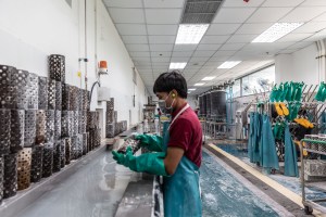 A male employee holds a casting container containing silver jewerly that has been cooled in the tank of water.
