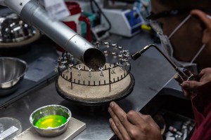 An employee uses a torch to treat jewelry.
