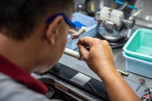 An employee works with enamel on a ring.