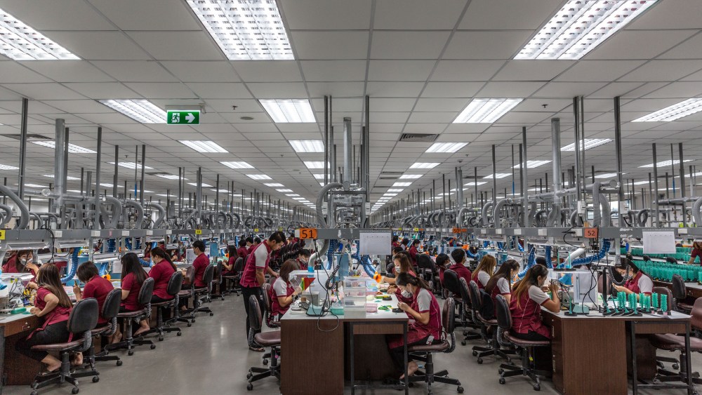 Employees use precision tools to set gemstones into wax “trees” that will hold them in place.