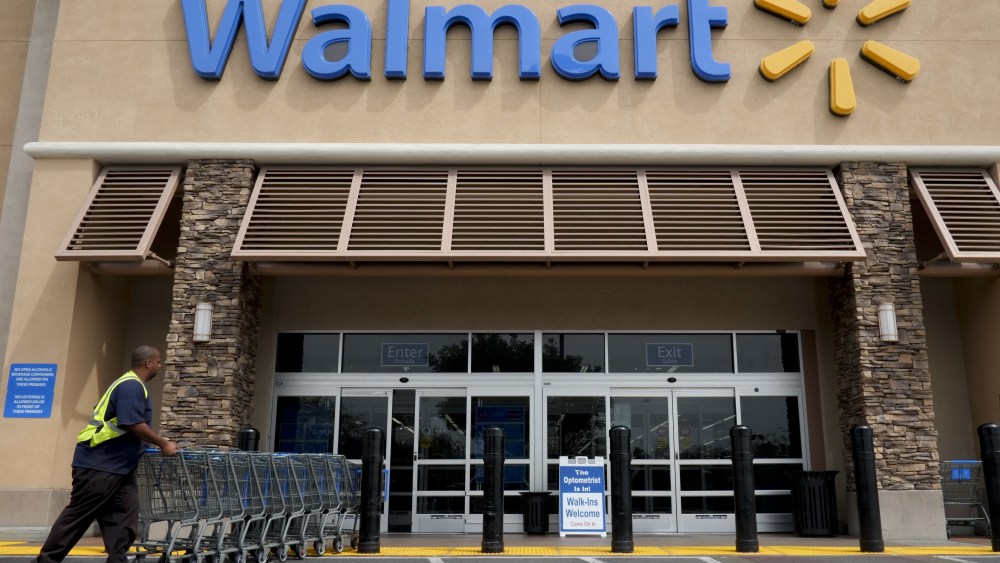 A worker pushes shopping carts in front of a Wal-Mart store in La Habra, Calif. Wal-Mart Stores Inc. is forming a partnership with China's largest online direct retailer, giving JD.com ownership of its Yihaodian marketplace platform assets, including the brand, website and appWal Mart Stores JDcom, La Habra, USA