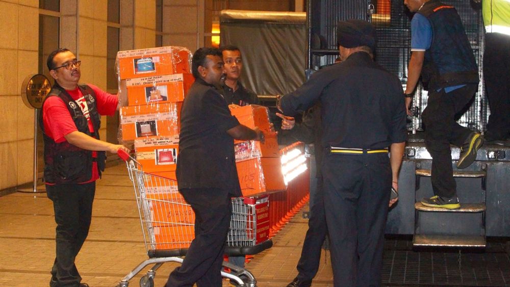 Police load confiscated orange Hermes boxes in a sting operation against Najib Razak.