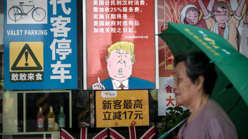 A woman passes by a restaurant with a poster depicting US President Donald J. Trump, stating that all US costumers will be charged 25 percent more than other customers starting from the day president Trump started the trade war with China, in Guangzhou, Guangdong Province, China, 13 August 2018. US President J. Trump announced on 10 July that US is preparing to impose 10 percent tariffs worth 200 billion US dollars on imported goods from China. These tariffs would affected mainly consumer goods.US-China trade war, Guangzhou - 13 Aug 2018