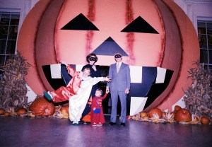 President Jimmy Carter, First Lady Rosalynn Carter, their daughter Amy, and their grandson Jason pose for a group portrait in front of a large pumpkin on the North Portico during a White House Halloween party.