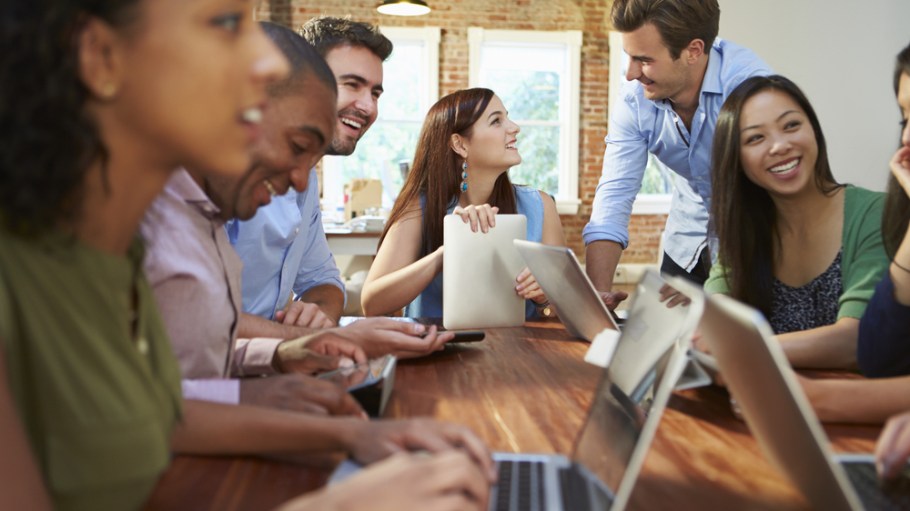 young people sitting at a table with computers collaborating