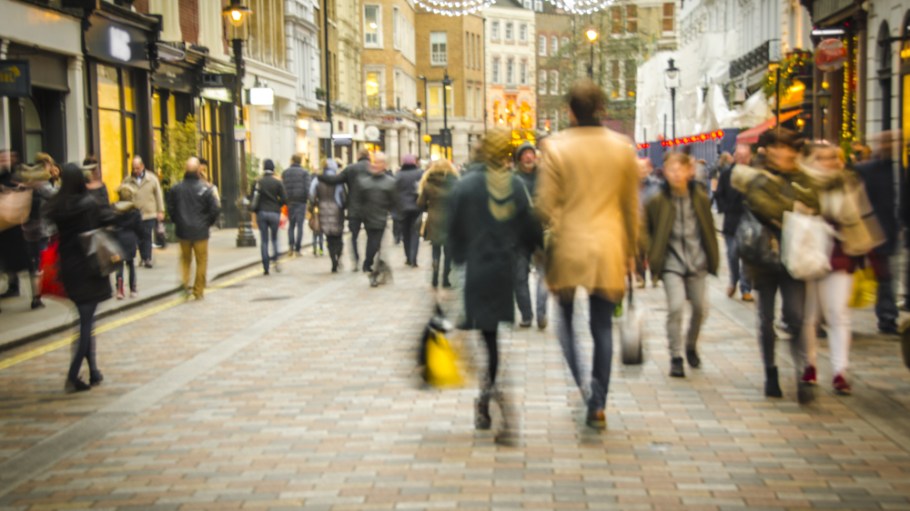 Shoppers strolling busy London high street with Christmas lights