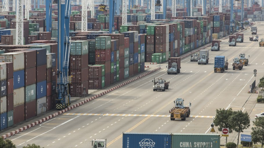 Containers sit stacked next to gantry cranes as trucks operate at the Port of Ningbo-Zhoushan in Ningbo, China.