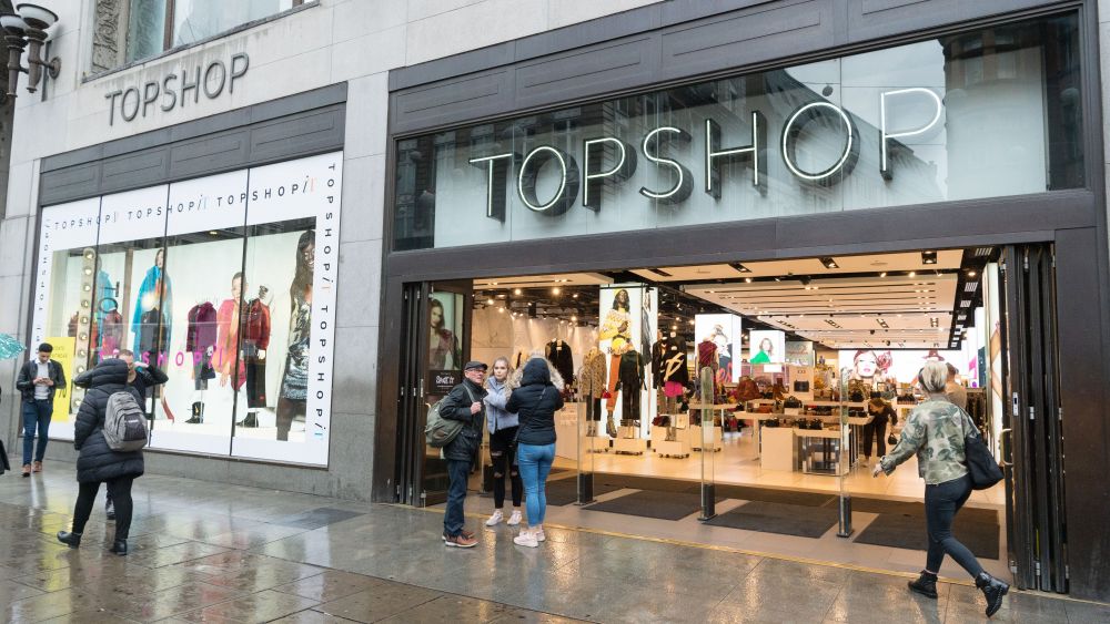 A woman holding an umbrella walks past the Topshop flagshop store in Oxford Circus as it opens for customers.Top Shop business continues after Sir Phillip Green Allegations, London, UK - 26 Oct 2018