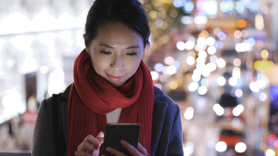 Woman use of mobile phone in city over traffic background