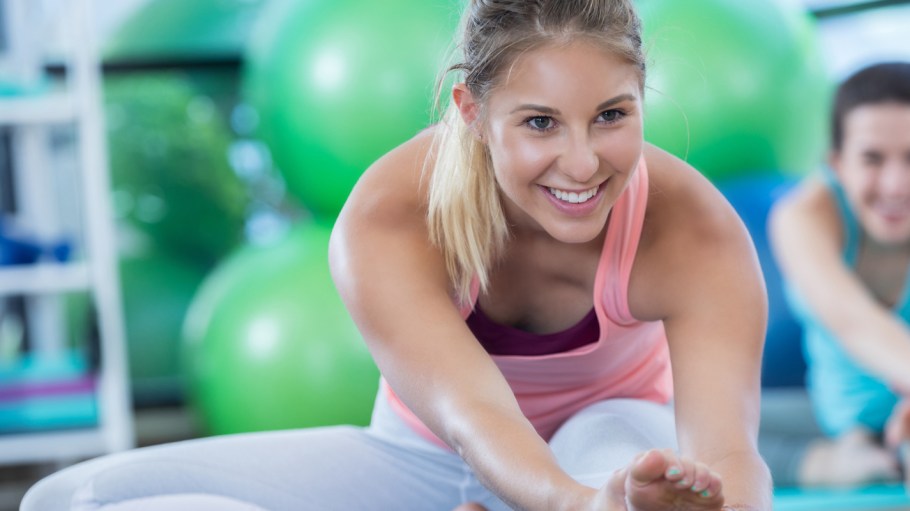 woman stretches to touch her toes while warming up before a workout