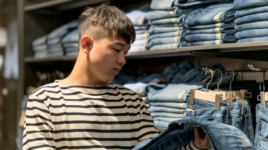 Teenage boy shopping for clothes in a discount store.