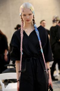Guido Palau interpreted the collectionÕs dark romance theme through a nod to gothic girls. He conceived different takes on a severe, middle-parted style by dyeing the modelsÕ manes in jet black or baby blond, as well as offering some graphic bobs. The most notable looks were the super-long side braids Ñ reminiscent of Wednesday Addams Ñ he created by carefully applying iron-straightened extensions and molding tresses with Redken Dry Shampoo Paste 05 styling paste. Trimmed extensions were used to enhance the volume of simpler ponytails, while the Redken Forceful 23 super-strength hairspray was key to secure the extreme hold on each mane.ÊÑ Sandra Salibian
