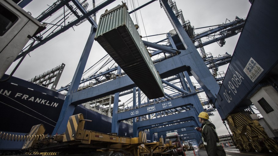 A dock worker directs the loading of shipping containers onto CMA CGM SA's Benjamin Franklin container ship docked at the Guangzhou Nansha Container Port in Guangzhou, China.