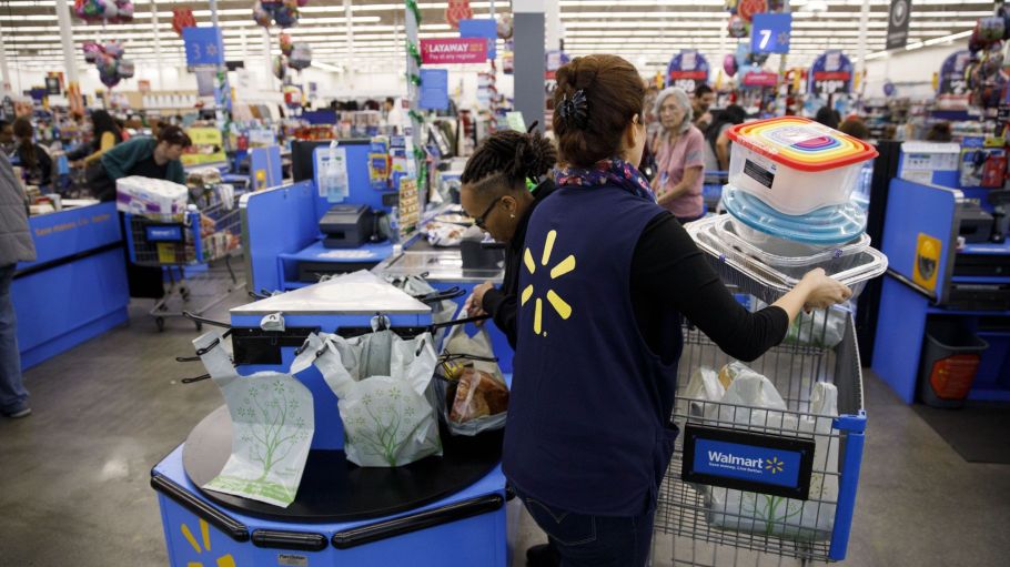 An employee places items into a customers shopping cart inside a Walmart Inc.
