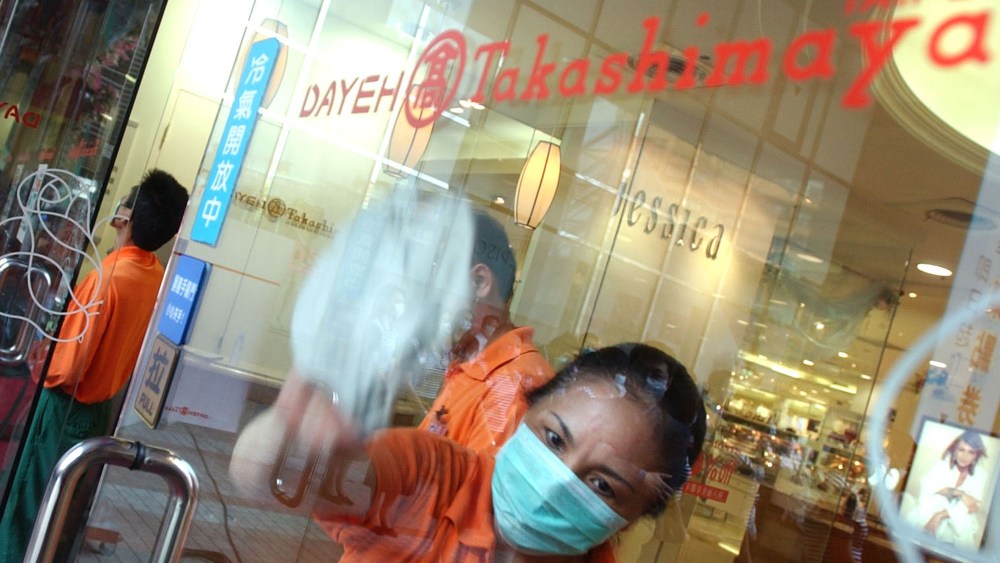 An employee wipes the glass doors of the Takashimaya department store