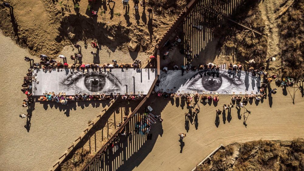 JR (French, born 1983). Migrants, Mayra, Picnic across the Border, Tecate, Mexico—U.S.A., 2017. Installation image. Wheat-pasted poster on table. © JR-ART.NET