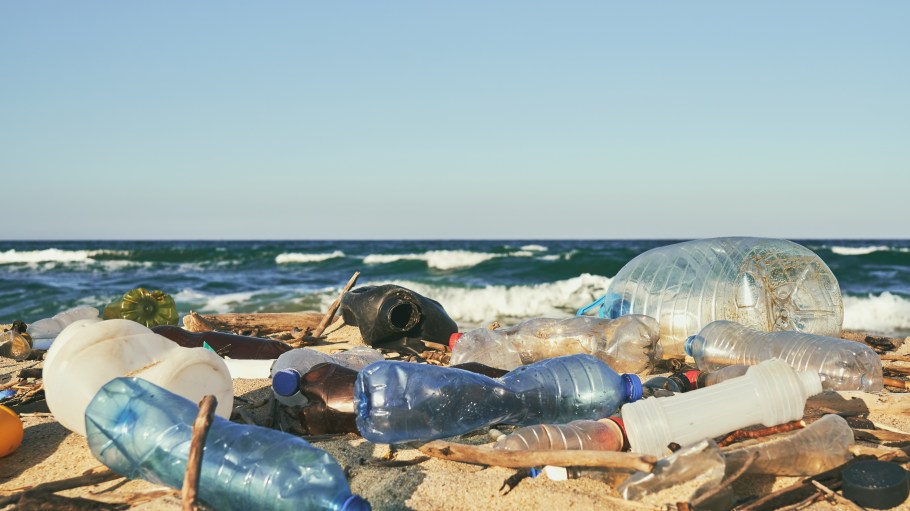 Spilled garbage on the beach of the big city. Empty used dirty plastic bottles. Dirty sea sandy shore the Black Sea. Environmental pollution. Ecological problem. Moving waves in the background