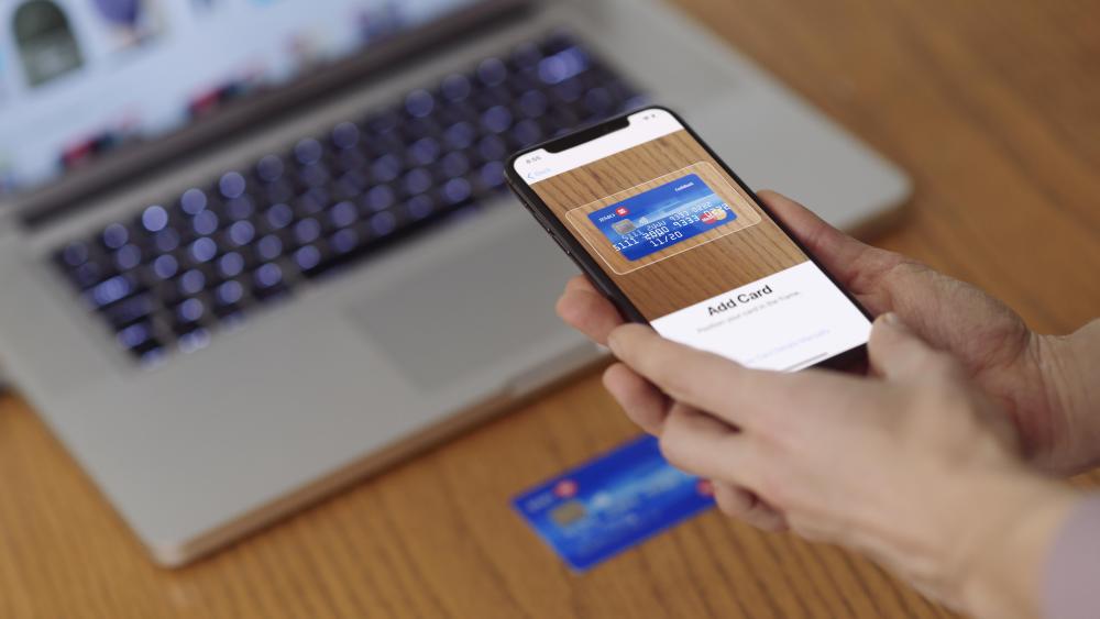 MODEL RELEASED Woman with iPhone X smartphone in her hand scanning a credit card with Apple Pay, Apple Wallet electronic payment appVARIOUS