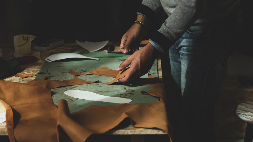 Close up of a shoemaker cutting leather.