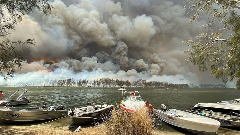 Boats are pulled ashore as smoke and wildfires rage behind Lake Conjola, Australia, . Thousands of tourists fled Australia's wildfire-ravaged eastern coast Thursday ahead of worsening conditions as the military started to evacuate people trapped on the shore further southWildfires, Conjola, Australia - 02 Jan 2020