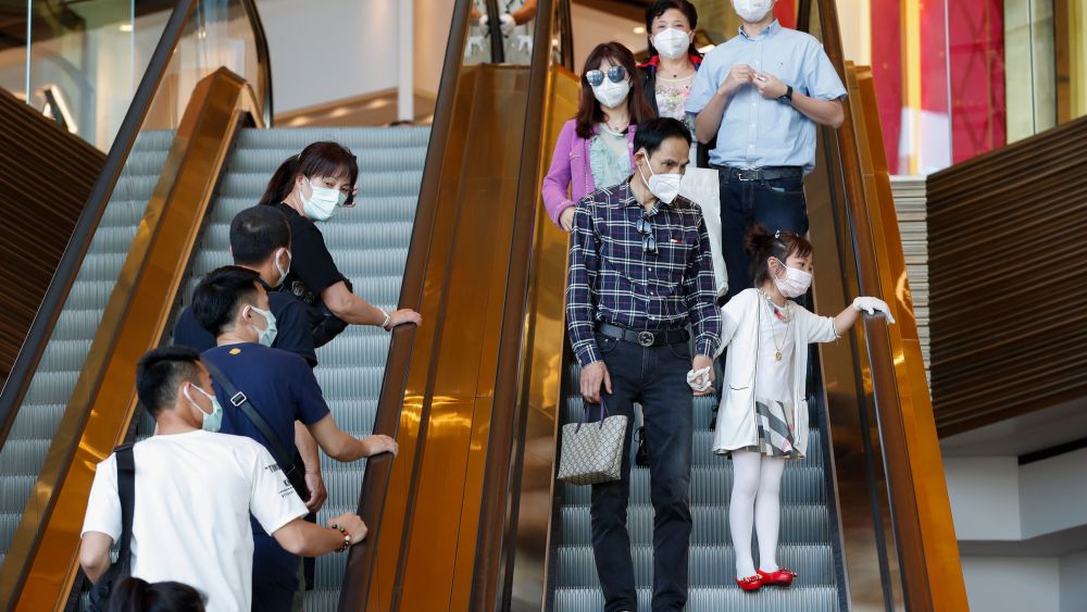 People wear protective masks while riding an escalator at a shopping mall.
