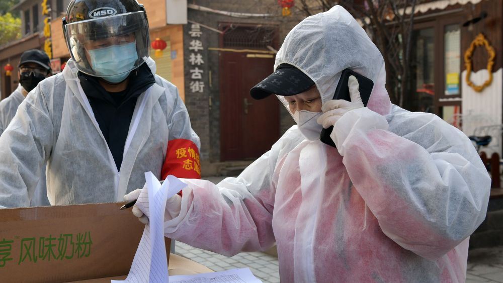 A community worker makes a phone call to dispense daily necessities to local residents at Tanhualin community in Wuchang District in Wuhan.