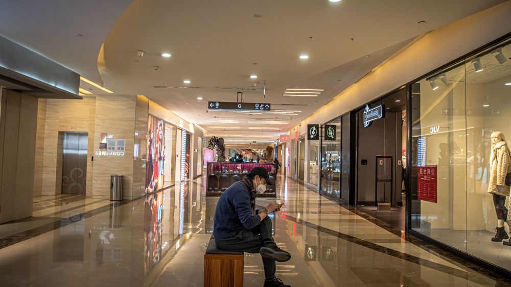 A man wearing a protective face mask sits in an almost empty mall in Beijing.