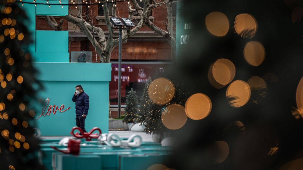 A man wearing a face mask walks past giant New Year and Christmas decoration outside a shopping mall in Shanghai, China.