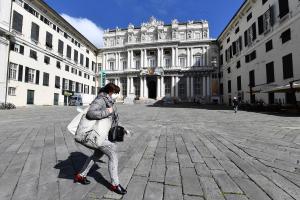 A woman wearing a protectve mask walks by in an almost deserted Ducal Palace square in Genoa, Italy.