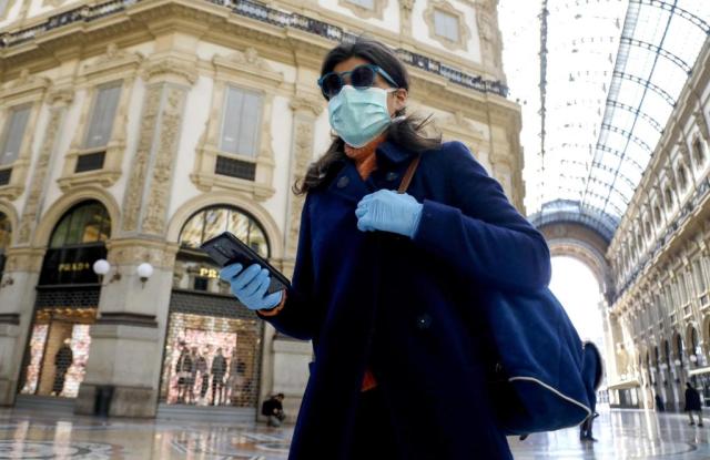 A woman wearing a face mask walks past the deserted Galleria Vittorio Emanuele II amid coronavirus outbreak, in Milan, Italy, 11 March 2020.Coronavirus in Italy, Milan - 11 Mar 2020